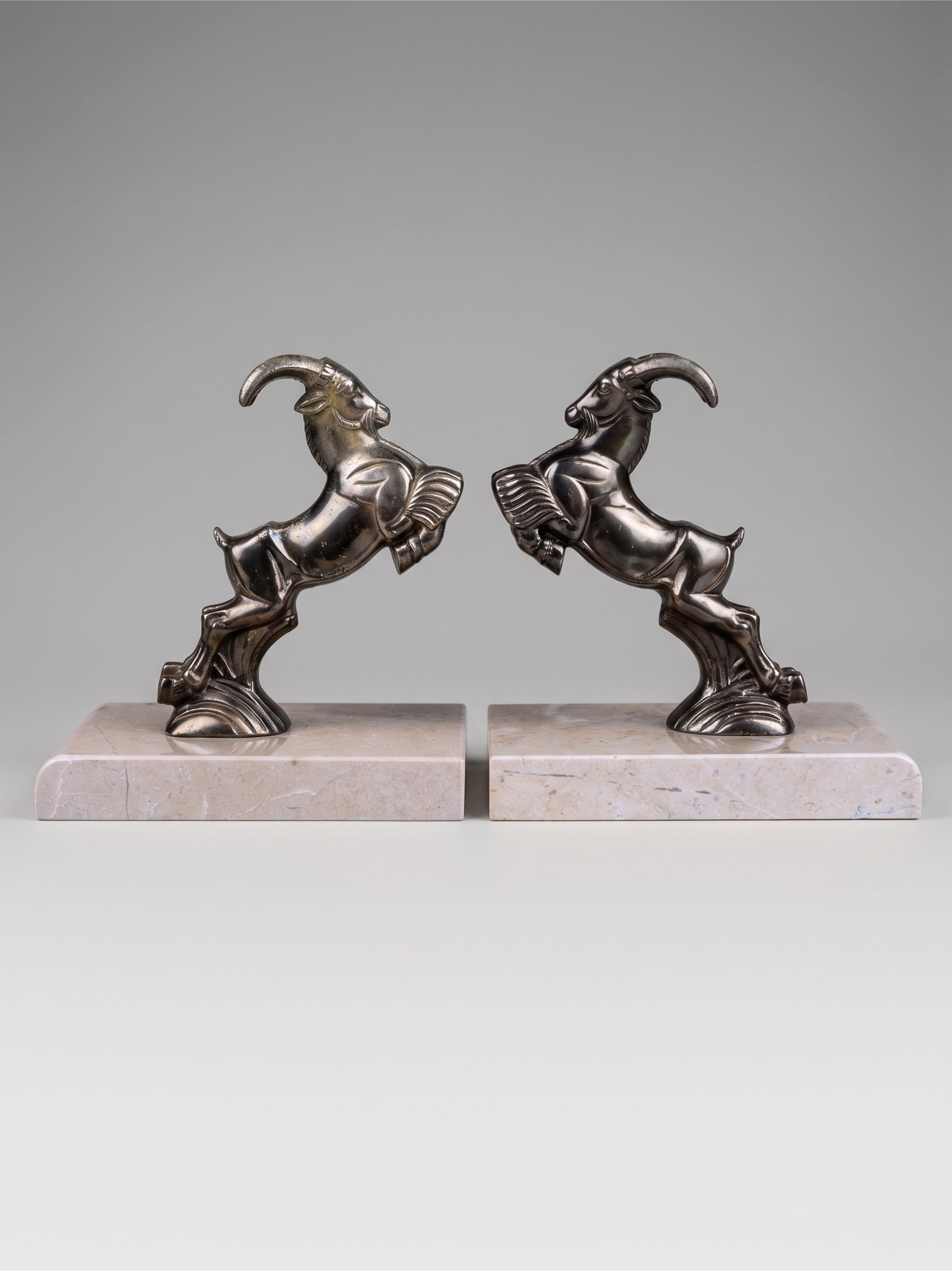 Art Deco ibex bookends in patinated spelter on taupe marble base – pair from the 1930s