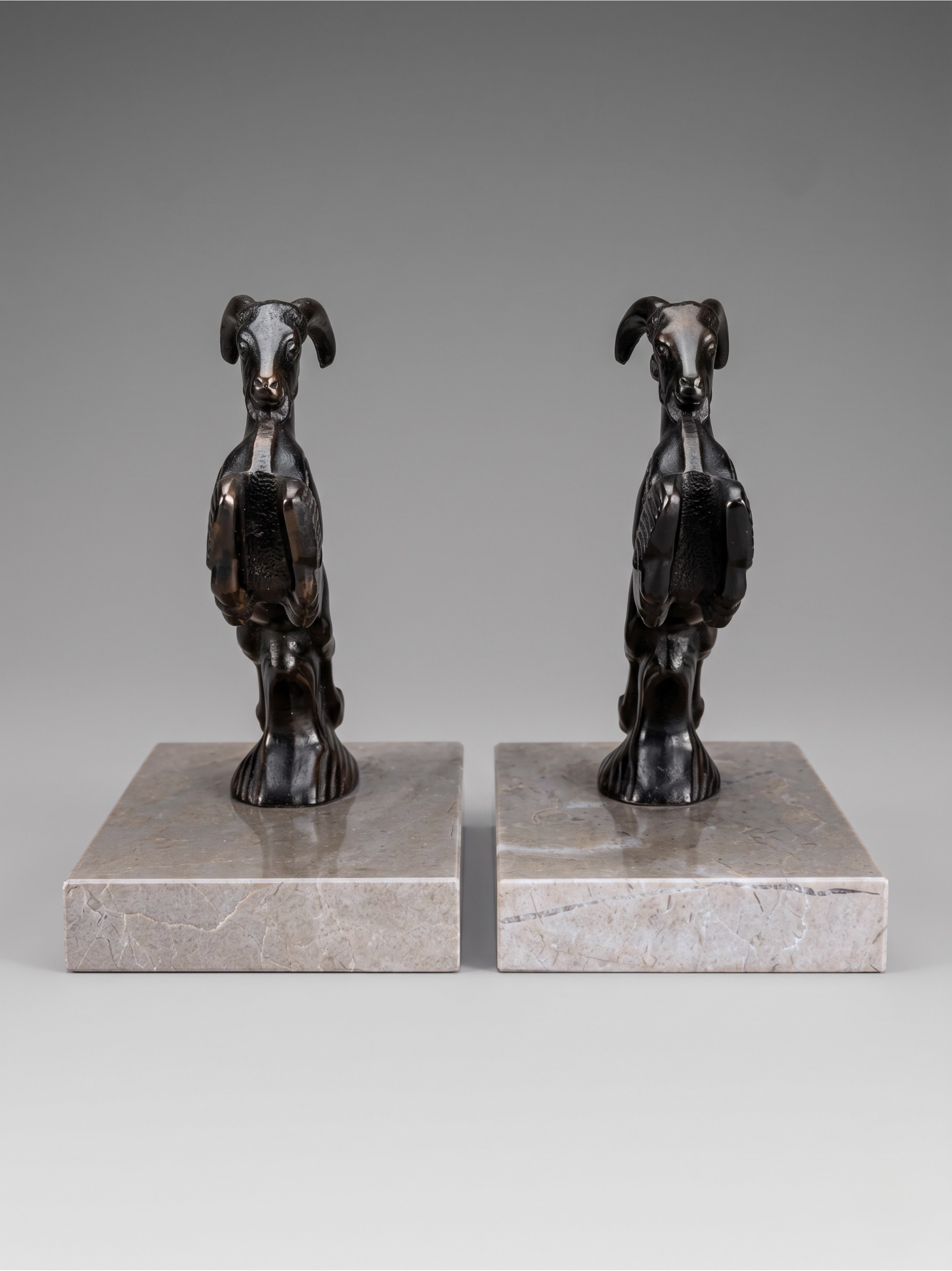 Art Deco ibex bookends in patinated spelter on taupe marble base – pair from the 1930s