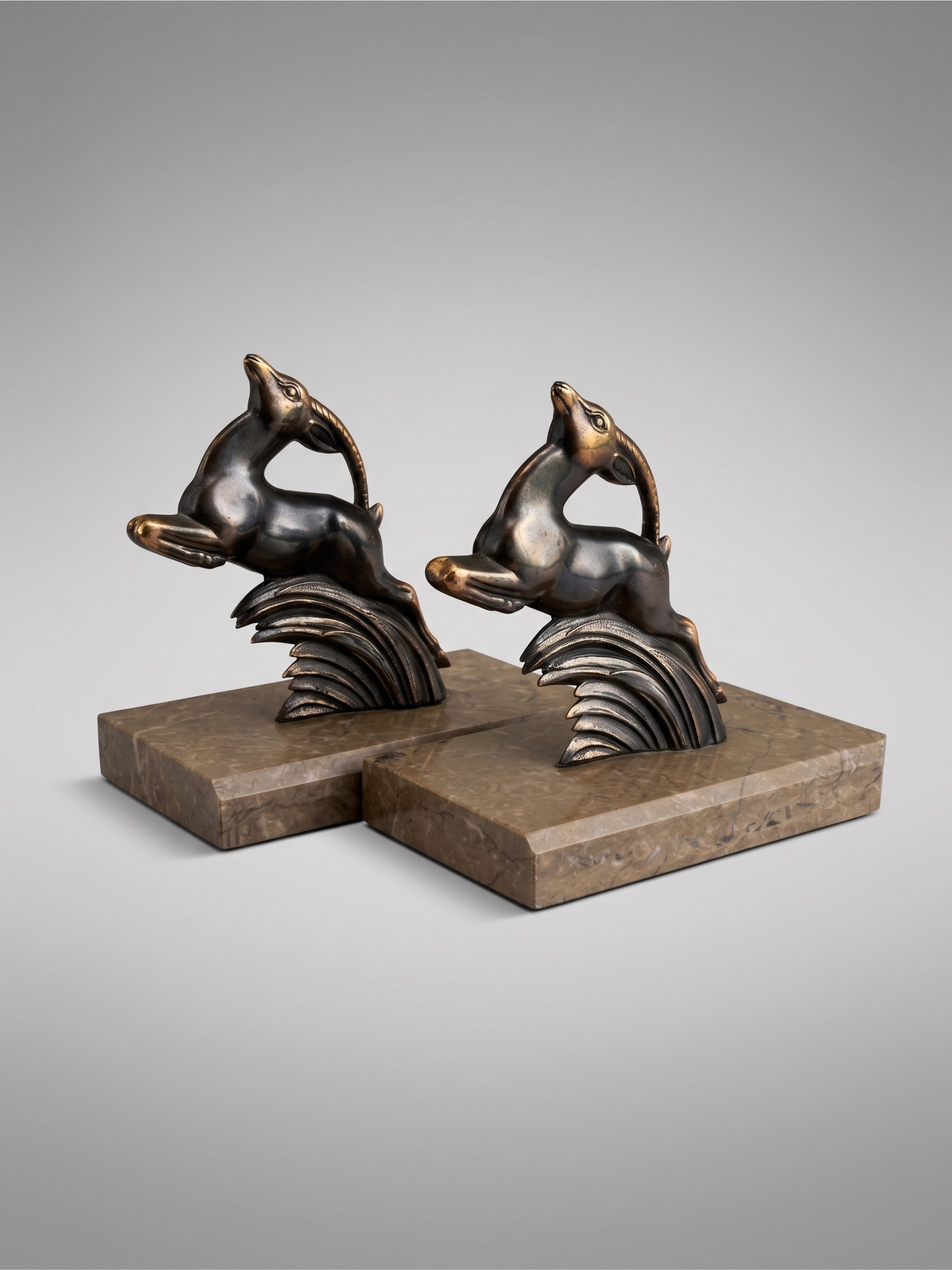 Art Deco bookends in patinated spelter – stylized animal pair – taupe marble bases – 1930s