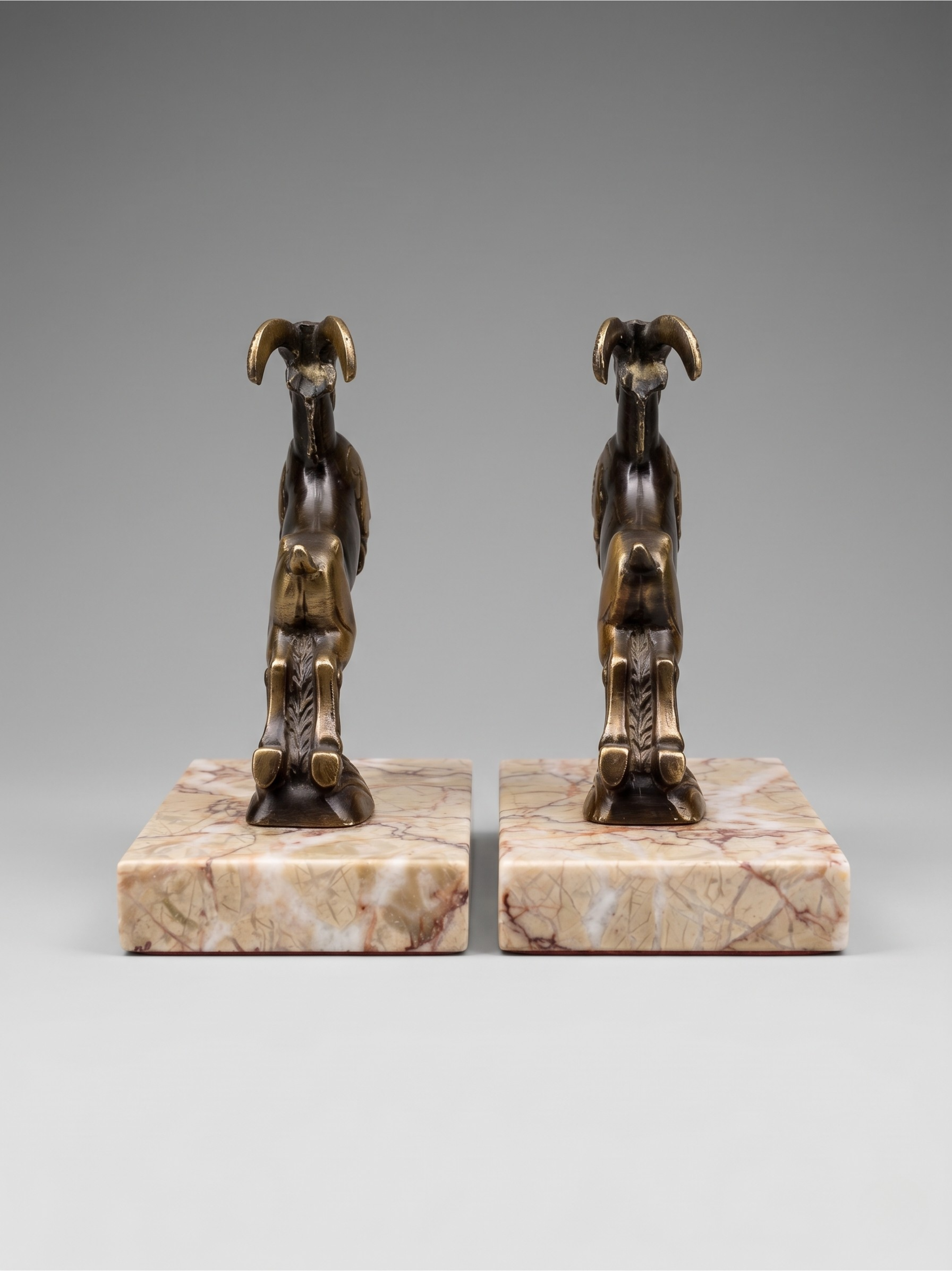 Pair of Art Deco ibex bookends in patinated spelter and veined marble, 1930s