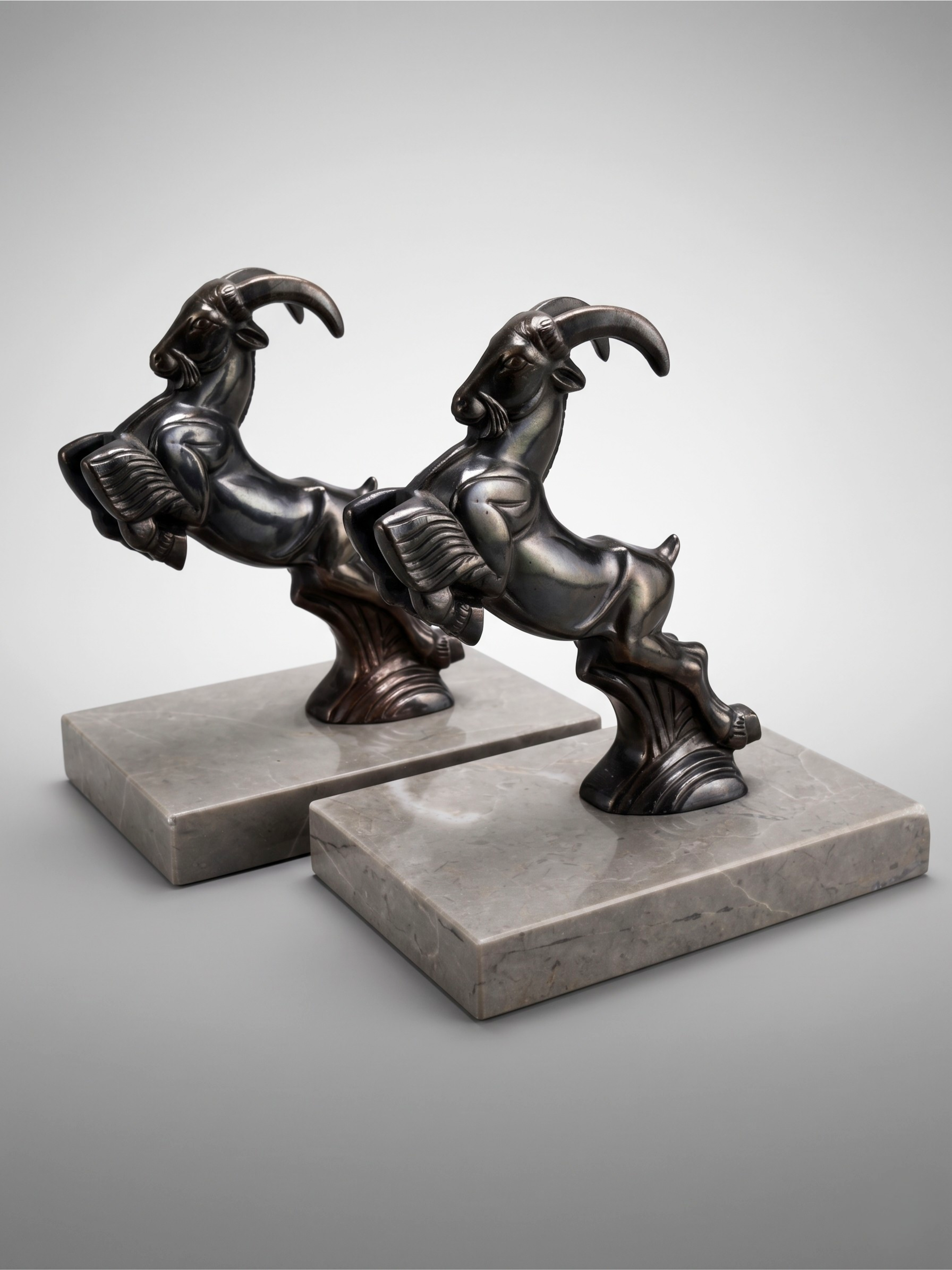Art Deco ibex bookends in patinated spelter on taupe marble base – pair from the 1930s